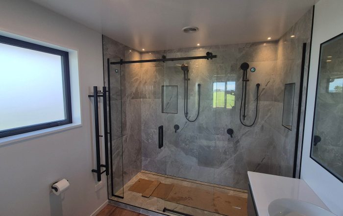 Luxury bathroom with marble tiled walk-in shower and black framed glass doors