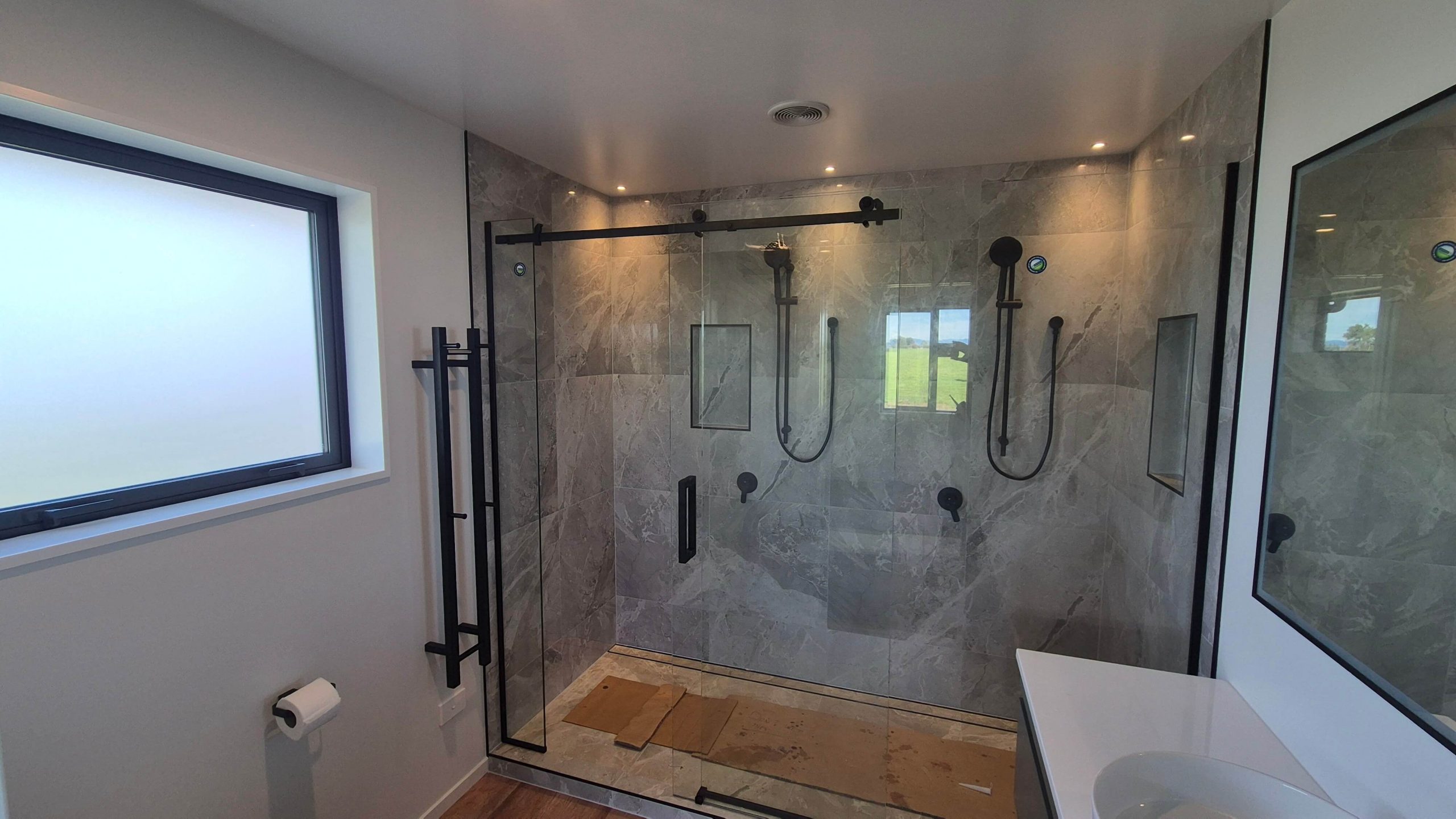 Luxury bathroom with marble tiled walk-in shower and black framed glass doors