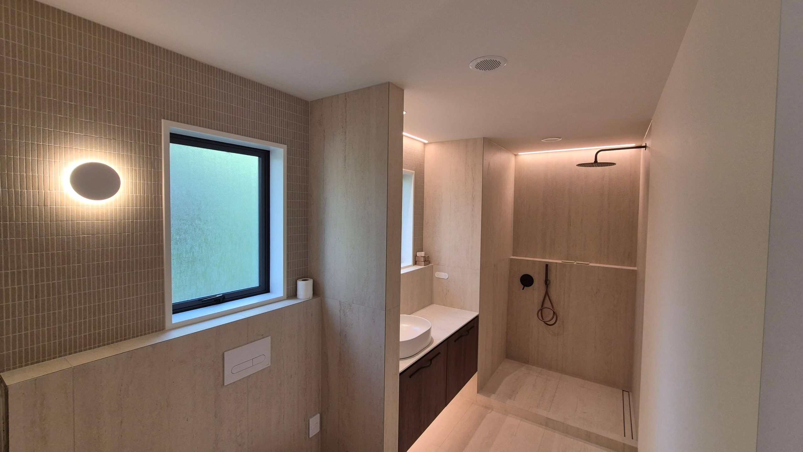 Modern spa-style bathroom with beige stone tiles and walk-in shower
